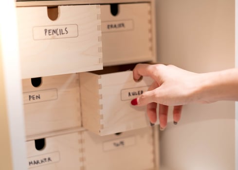 Female hand opening drawer with office tools that put on the wood shelf in the room. photo