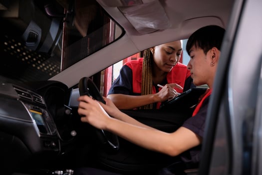Young male Asian automotive mechanic technician and partner checking maintenance list with tablet in car interior at garage. Vehicle service fix and repair works, industrial occupation business jobs. photo