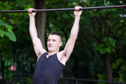 strong man doing pull-ups on a bar outdoor photo