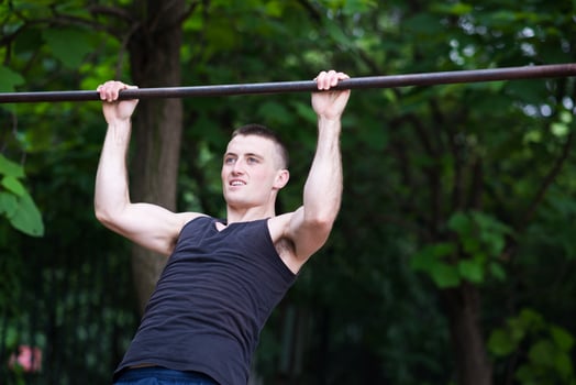 strong man doing pull-ups on a bar outdoor photo