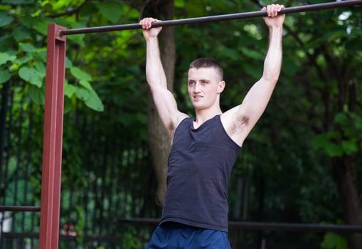 strong man doing pull-ups on a bar outdoor photo