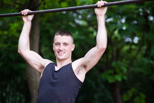 strong man doing pull-ups on a bar outdoor photo
