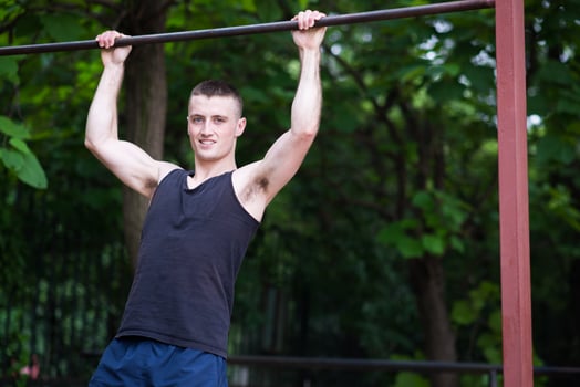 strong man doing pull-ups on a bar outdoor photo