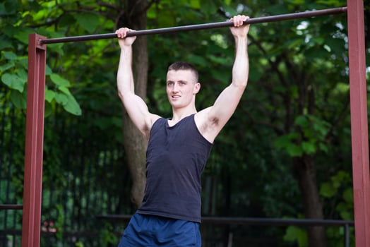 strong man doing pull-ups on a bar outdoor photo