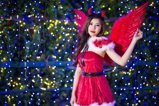 Portrait of beautiful young Santa woman on bright lights background photo