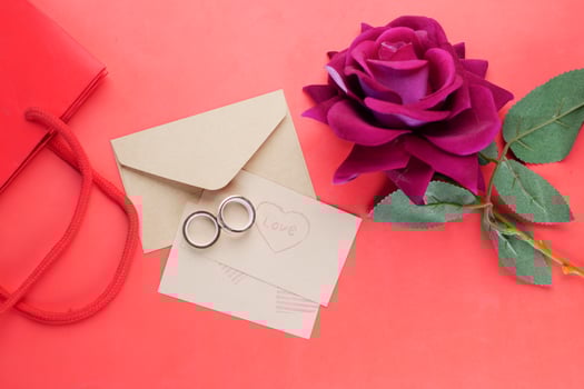 wedding ring and gift box and rose flower on red photo
