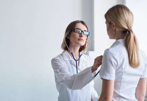 Woman doctor with stethoscope and glasses examines the patient health model photo