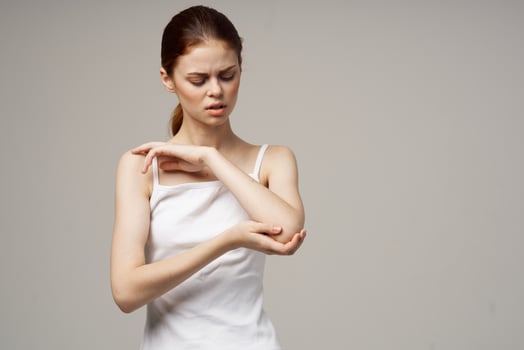 disgruntled woman elbow pain arthritis chronic disease light background photo