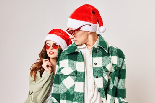 Cute young couple wearing sunglasses Christmas hats fun holiday photo