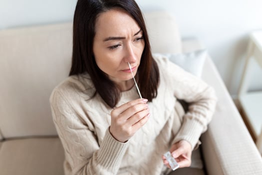 Shot of a woman using cotton swab while doing coronavirus PCR test. Woman takes coronavirus sample from her nose at home. woman at home using a nasal swab for COVID-19. photo