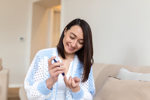 Asian Woman using lancelet on finger. woman doing blood sugar test at home in a living room. photo