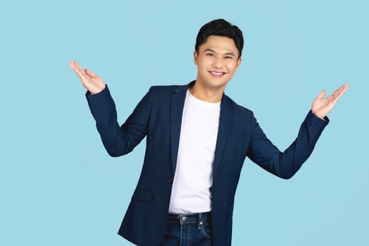Excited surprised handsome young Asian man doing open hand gesture isolated on light blue background photo