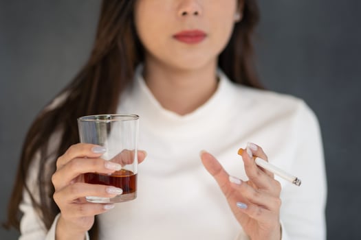 Asian woman hand drinking glass of alcohol and smoking cigarette photo