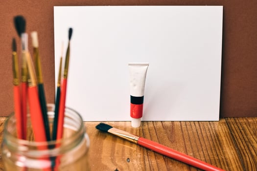 A white board with a tube of paint and a jar of paint photo