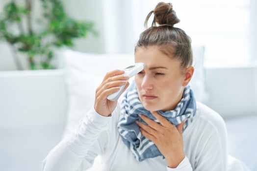 Young brunet woman sick in the bed with thermometer photo