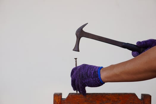Closeup carpenter hand uses hammer to hit nail. Concept, carpentry and construction tools. Repair or fixing, DIY woodwork. photo
