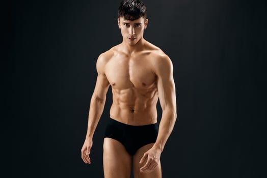 a man in dark shorts with a muscular body on a dark background bodybuilder photo