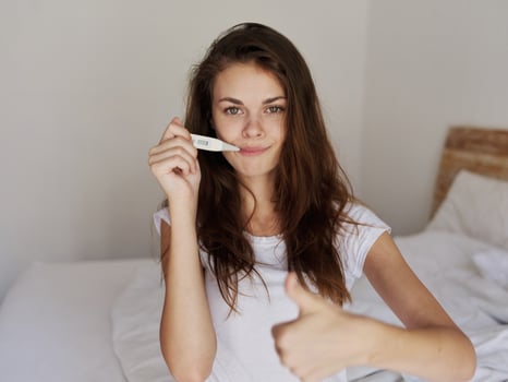 woman with a thermometer in her mouth positive temperature photo