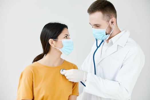 doctor in a medical gown examines a female patient in a blue mask photo