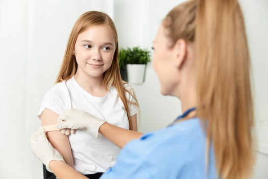 a female doctor next to a girl seals her arm with a plaster vaccination photo