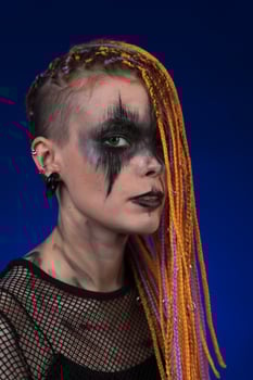 Dramatic portrait young woman with horror black stage makeup painted on face, dreadlocks hairstyle photo