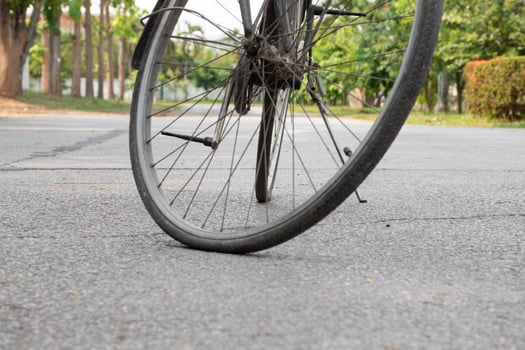 Closeup view of vintage bike which has flat wheels and parked on cement floor of street near the building, soft focus. photo