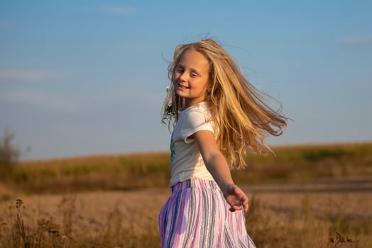 Beautiful little girl with a bouquet of wild flowers on a background of the sky. A happy child on a summer meadow. photo