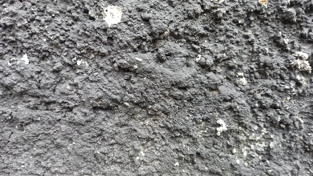 a close up of a black wall with some dirt photo