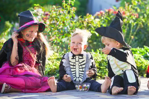 Young kids trick or treating during Halloween . Children are sitting on the road in halloween costumes. Copy space photo