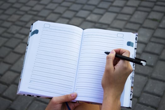 Close-up of a young girl writing into her diary, in the park photo