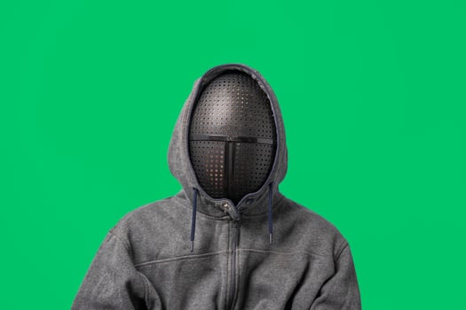an unrecognizable man in a gray hoodie with a mask on his face isolated on a green background photo