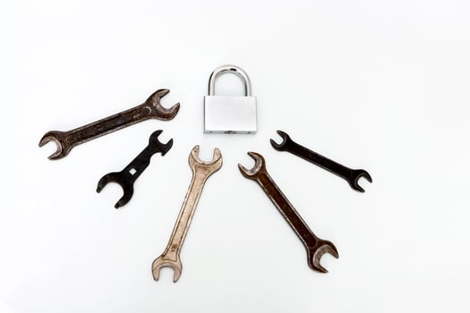 closed new shiny padlock surrounded by old rusty wrenches photo