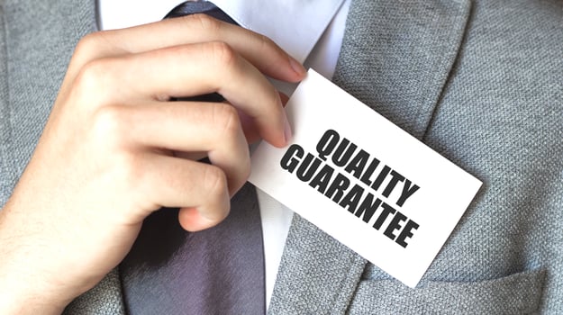 Businessman putting a card with text quality guarantee in the pocket photo