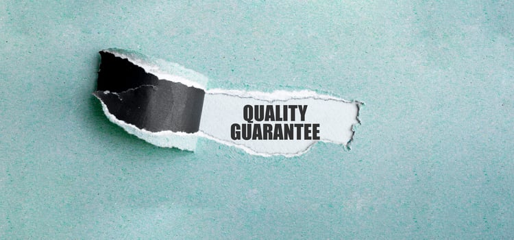 The text quality guarantee appearing behind torn green paper photo
