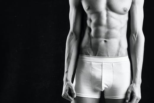 male athlete in white shorts inflated body bodybuilder the dark background photo