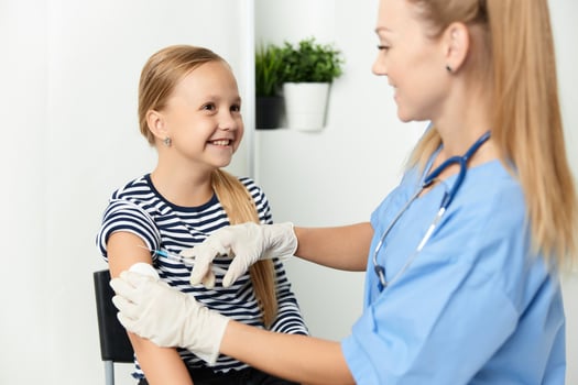 woman doctor in a blue coat injecting a child into the hand covid photo