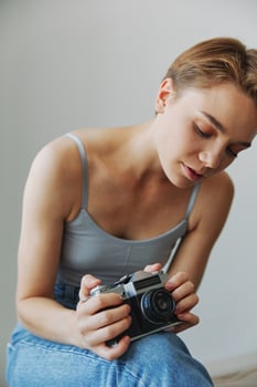 Woman photographer shooting in studio on old film camera at home on couch portrait, white background, free copy space, freelance photographer photo