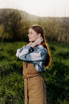 Young woman fixes her long red hair in nature in the sunset sunlight photo