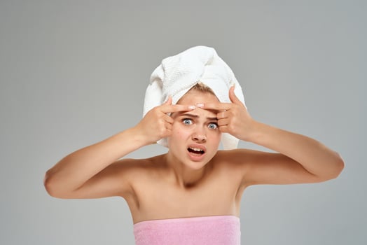 woman with bare shoulders and a towel on her head pimples on her face close-up photo