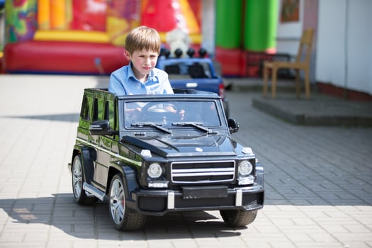 Funny boy in a children's car in the city. photo