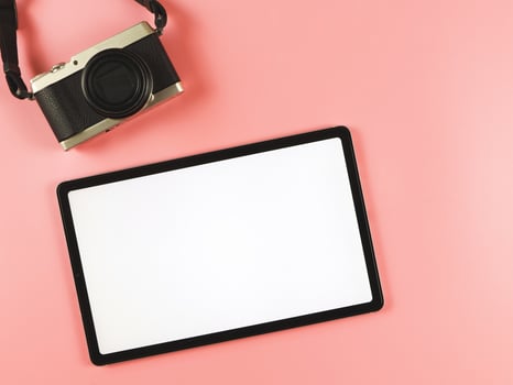 flat lay of digital tablet with blank white screen and digital camera isolated on pink background. photo