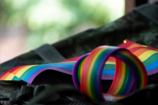 Rainbow flag and rainbow wristbands on camouflage background, concept for celebrations of LGBT people in pride month around the world, soft and selective focus on wristband. photo