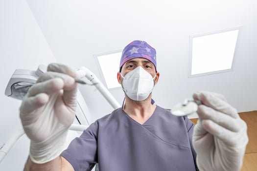 Dentist in mask checking teeth of patient photo