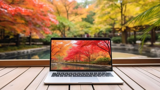 Blank screen laptop computer on terrace with beautiful autumn colorful red and yellow maple leaves background, photo
