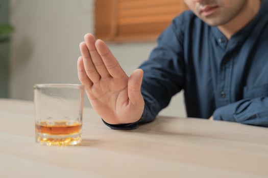 man refuses say no and avoid to drink an alcohol whiskey , stopping hand sign male, alcoholism treatment, alcohol addiction, quit booze, Stop Drinking Alcohol. Refuse Glass liquor, unhealthy, reject photo