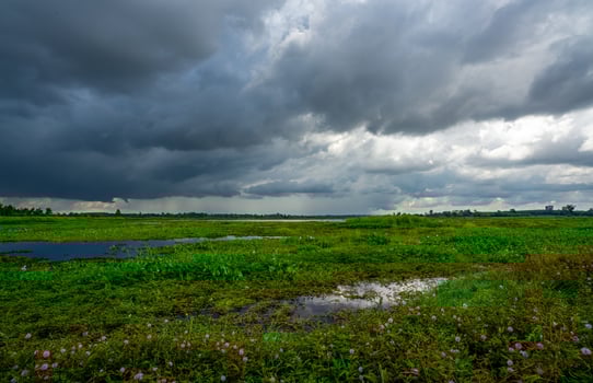 Landscape of green grass field and overcast sky. Dark cloudscape of a stormy sky. Natural water reservoir. Water sustainability. Freshwater for human consumption. Sustainable sources of water. photo