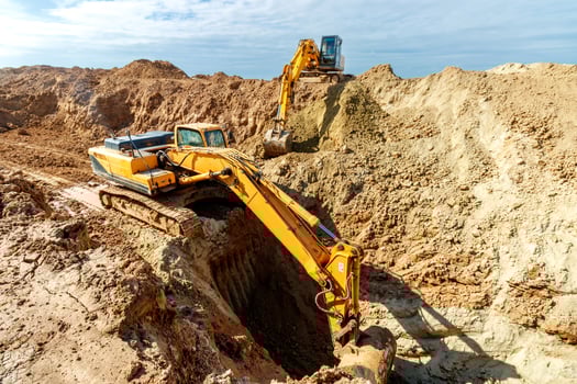 Two Excavator are digging soil in the construction site on sky background,with white fluffy cloud photo