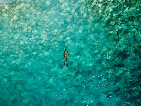 Aerial drone view of a person doing spearfishing on crystal blue water. Recreational fishing and summer activity. Summertime. photo