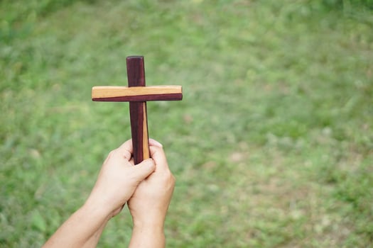 Closeup hands hold wooden cross, crucifix outdoor. Concept , Christian worship. Faith, forgiveness,belief, love and hope. Religious symbol of Christianity. photo