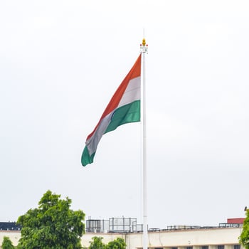 India flag flying high at Connaught Place with pride in blue sky, India flag fluttering, Indian Flag on Independence Day and Republic Day of India, tilt up shot, Waving Indian flag, Har Ghar Tiranga photo